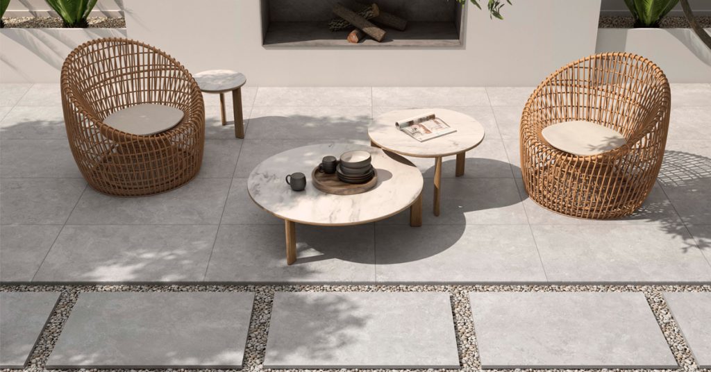 Fauteuils en rotin, tables rondes, sol carrelé gris