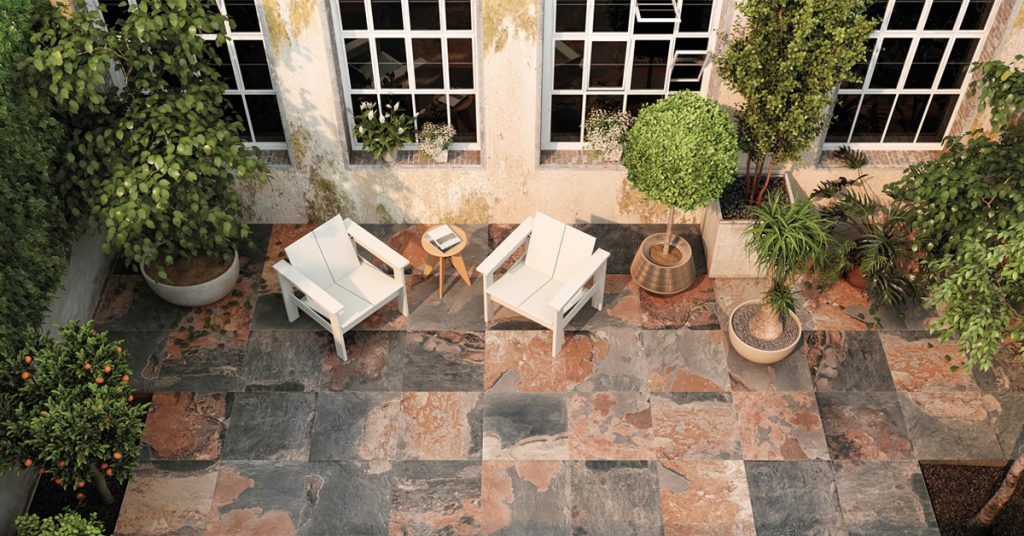 Patio avec carreaux gris-rouille, deux fauteuils blancs, plantes