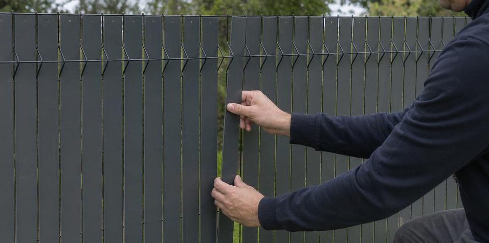 Mains tressant une latte PVC dans un panneau rigide