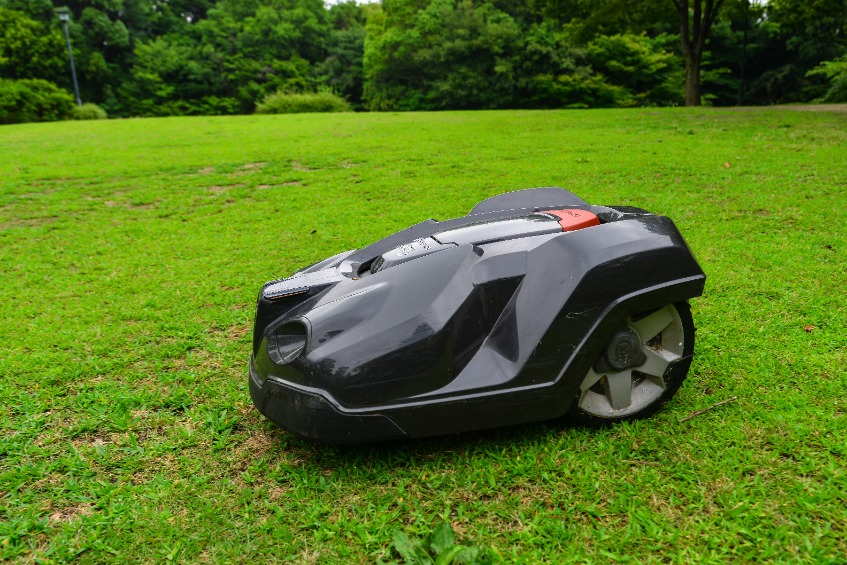 Tondeuse robotisée noire sur gazon, vue de profil en marche